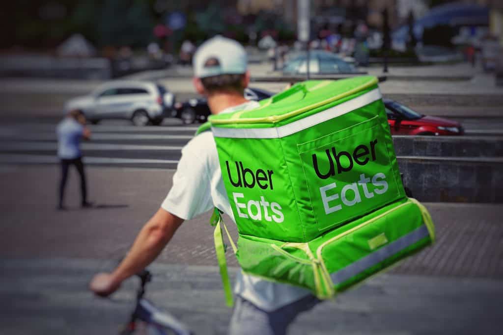 delivery person man on bike with Uber Eats backpack for food delivery service bicycle