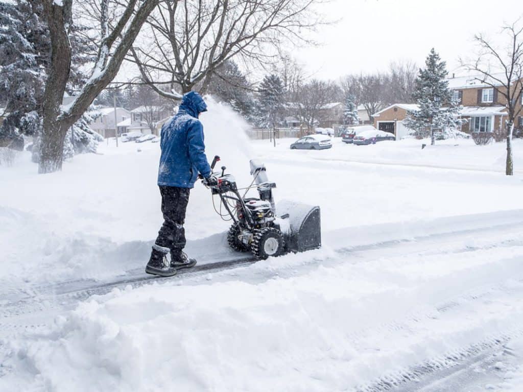 Man-Removing-Snow-with-a-Snowblower in a blue coat