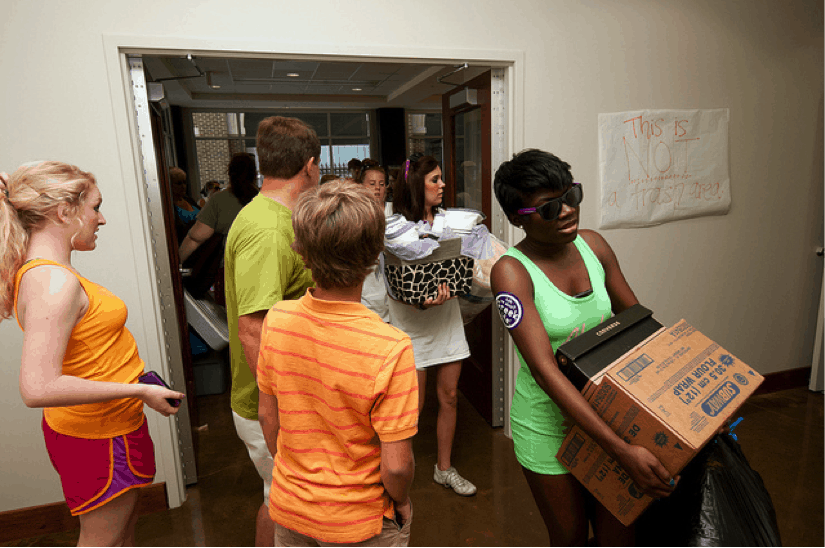 college students moving into dorm rooms carrying boxes