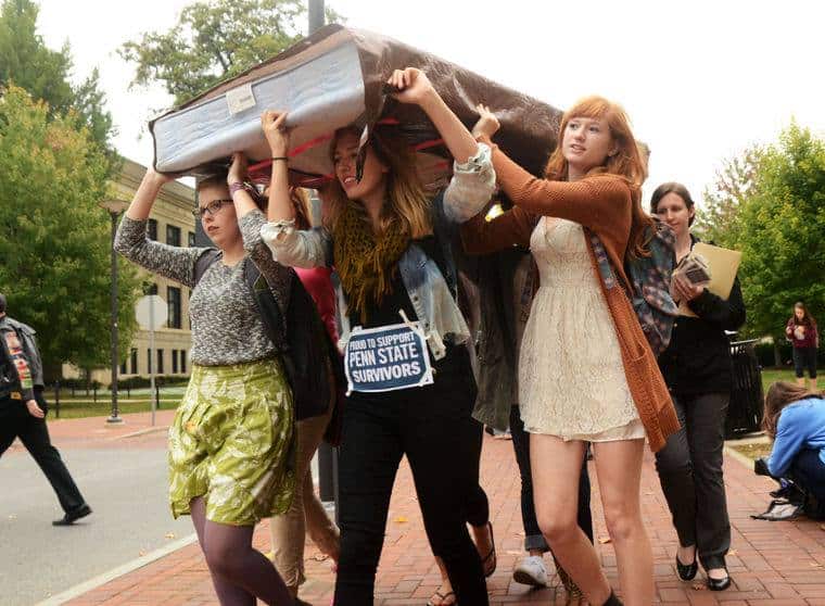 group of college girls carrying mattress down sidewalk on moving day