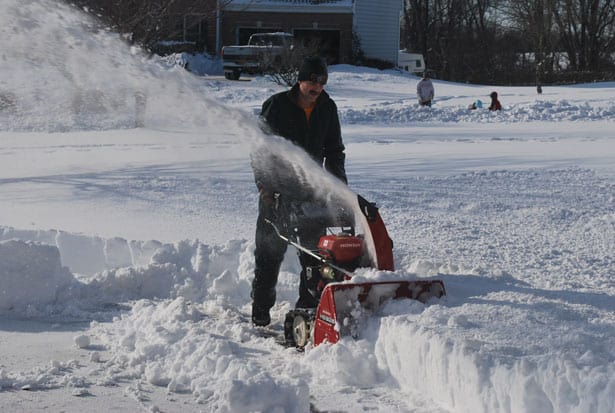 man with mustache clearing driveway with snow blower