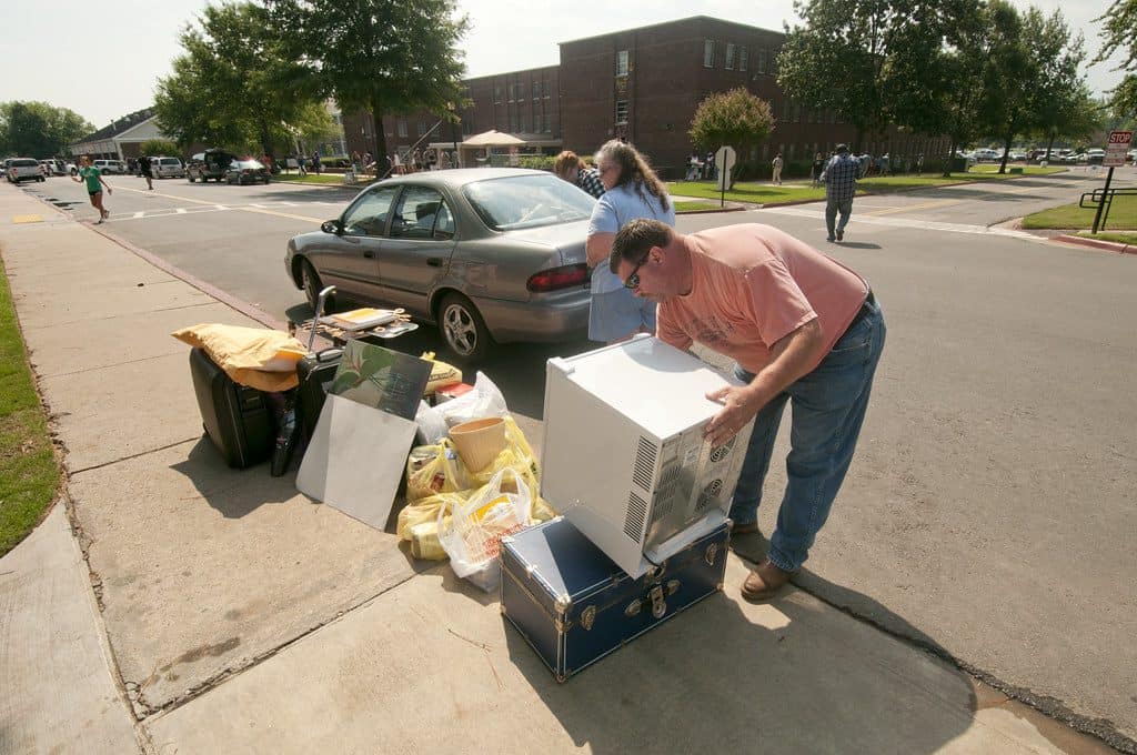 parents helping college student on moving day with lots of stuff on sidewalk