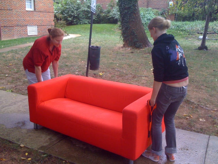 two college students girls moving small orange couch