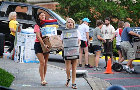 two college students girls roommates carrying boxes of stuff on moving day