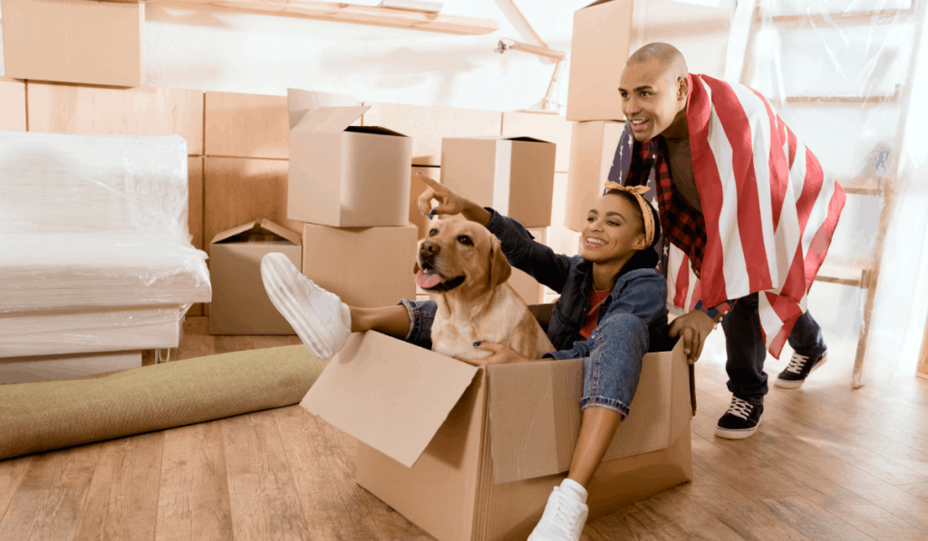 African american couple having fun with dog in new apartment