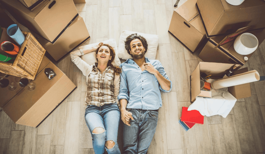 couple laying on floor surrounded by moving boxes moving to an apartment