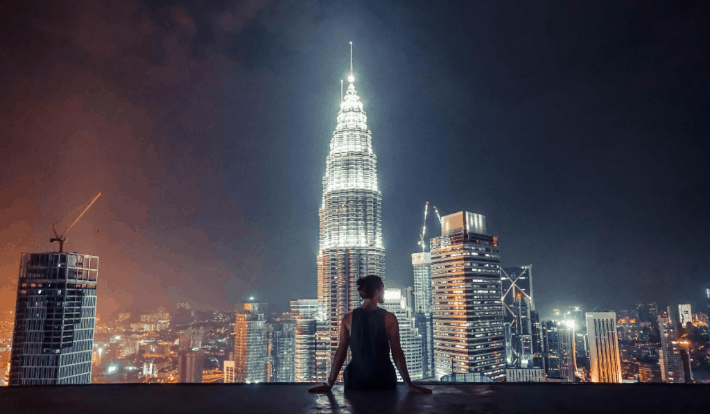 kuala lampur malaysia woman looking out on large city skyscraper lit up at night