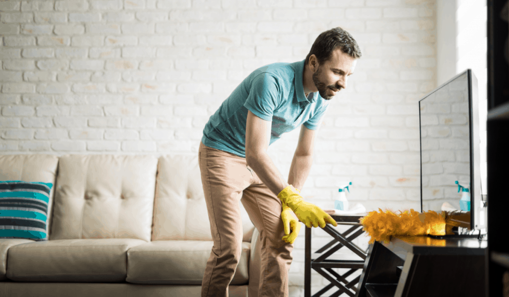 man cleaning apartment dusting entertainment center