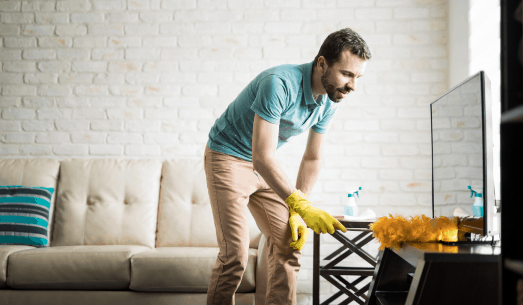 hombre limpiando apartamento quitando el polvo del centro de entretenimiento