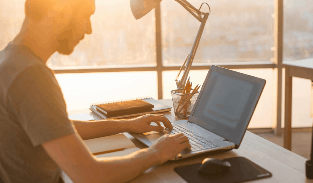 Mann arbeitet am Laptop in der Nähe des Fensters Golden Hour