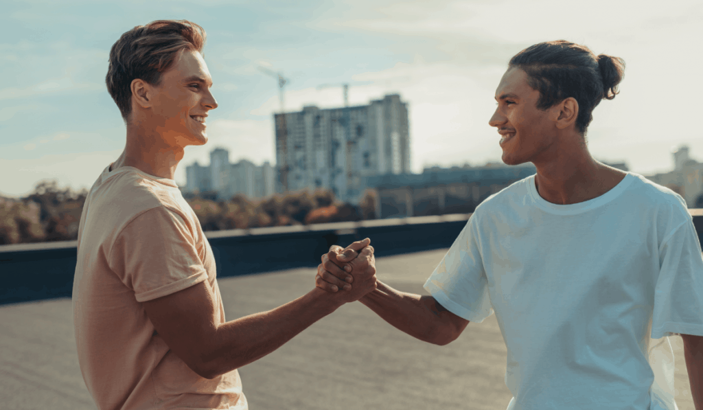 Due uomini che si stringono la mano e si afferrano sorridendo sul tetto