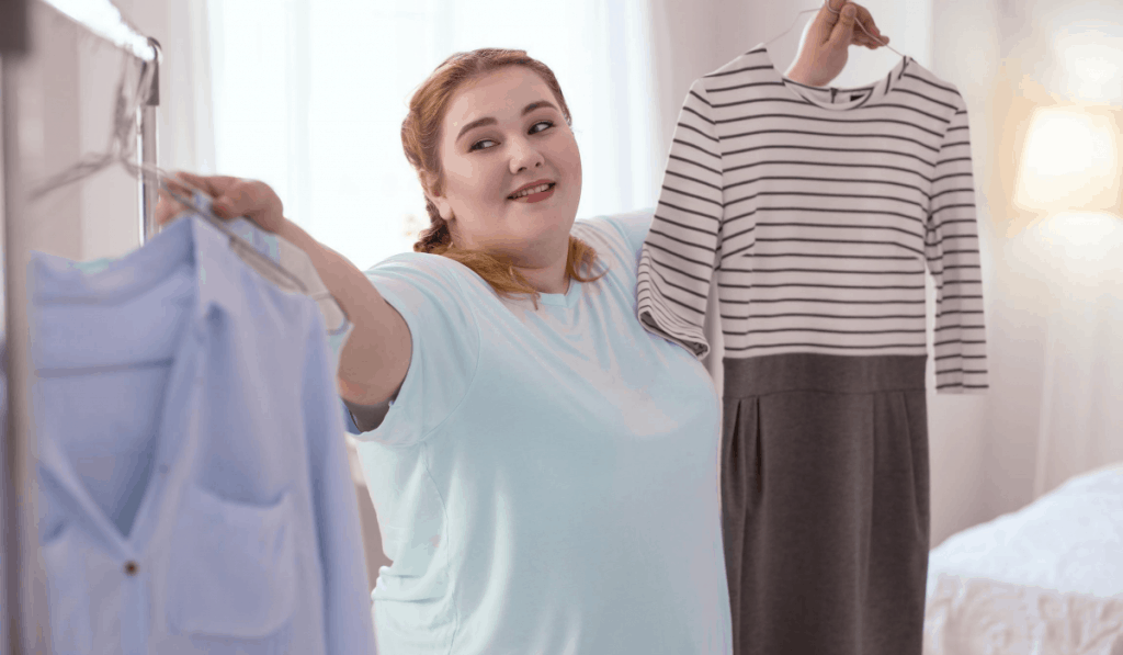 Mujer colgando una camisa en un perchero eligiendo conjuntos