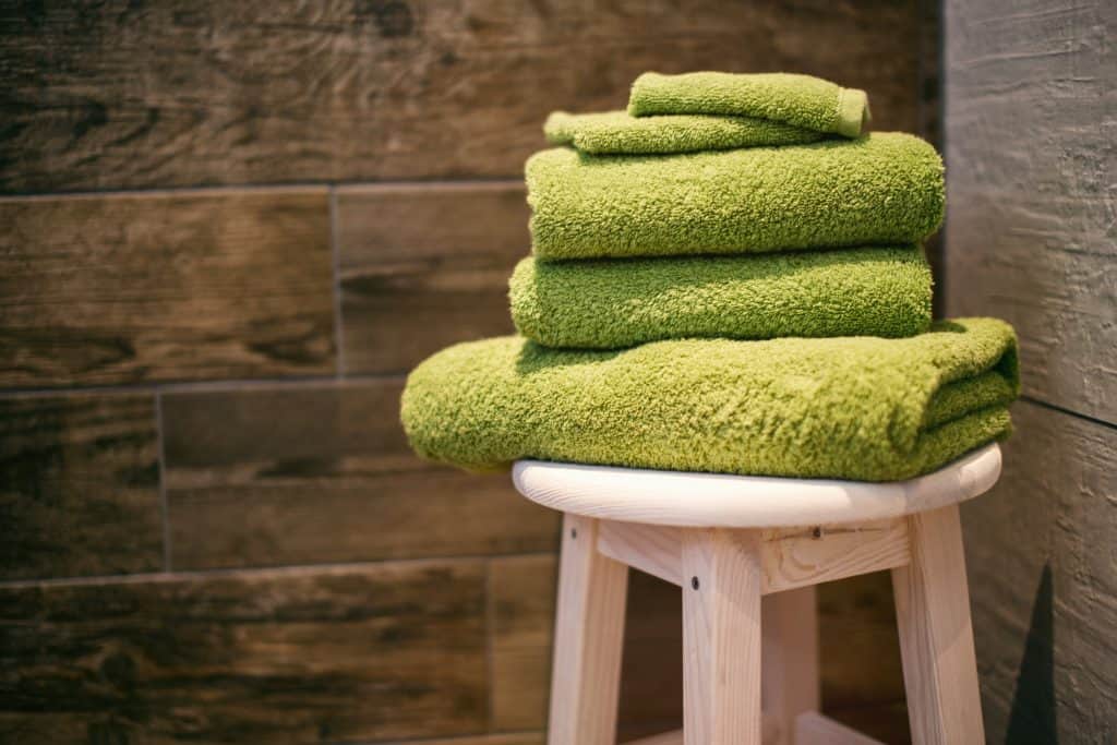 green towels folded on wooden stool