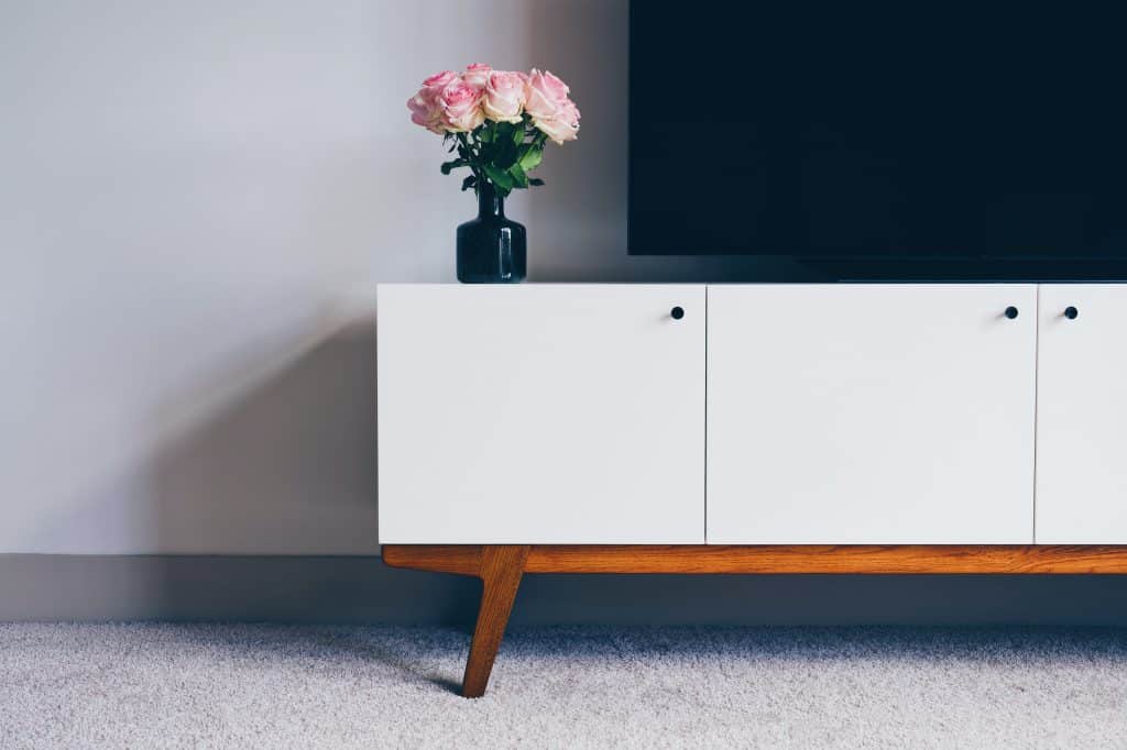 modern media console with flowers in vase and tv