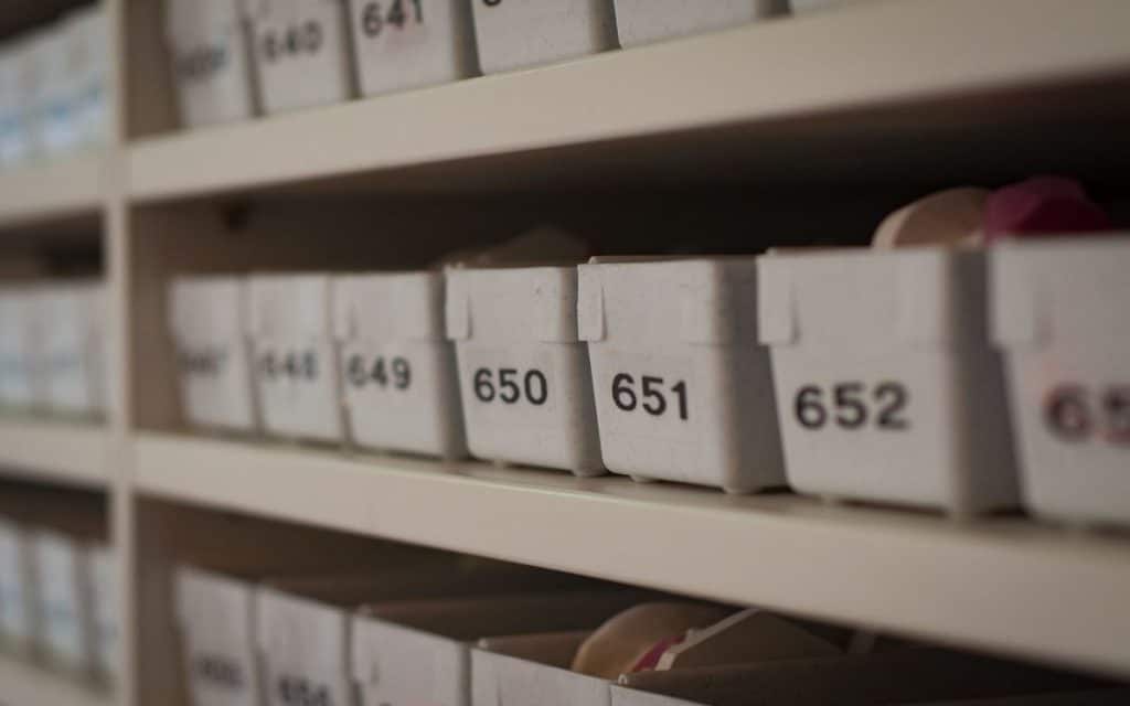 plastic storage bins on shelves with numbered inventory system