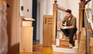 man moving out sitting on the stairs holding a table